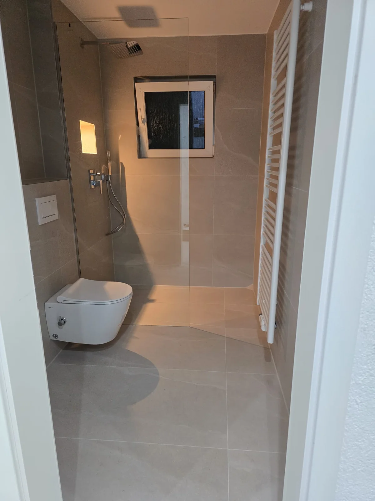 Der neue Duschbereich mit Glasabtrennung, Regendusche und schlankem Heizkörper.
