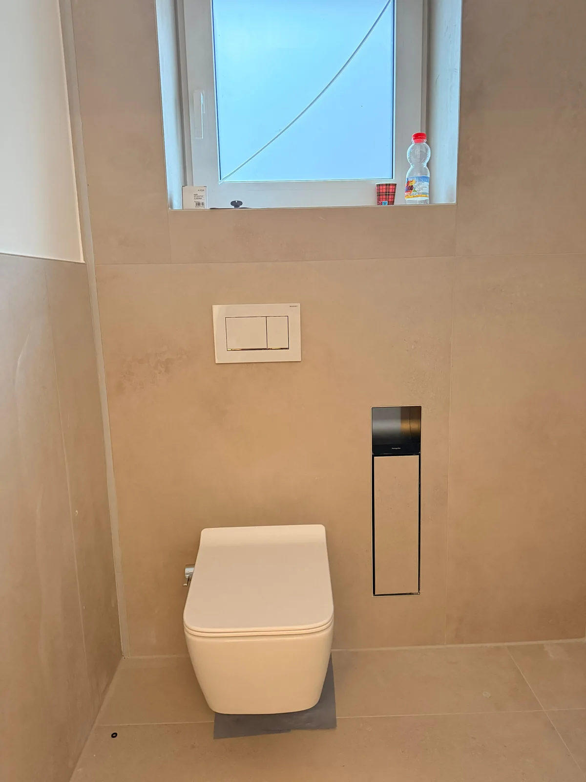 Neu montiertes WC mit Betätigungsplatte und wandintegriertem Zubehörmodul.